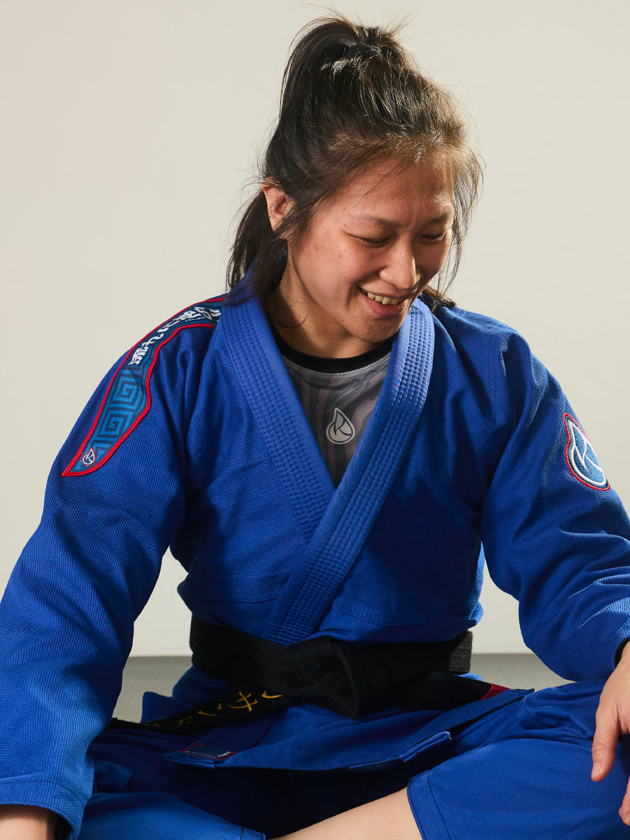Person wearing a blue martial arts uniform sitting on the floor.